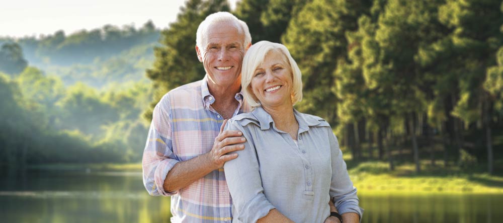 couple standing by lake smiling confidently mobile size